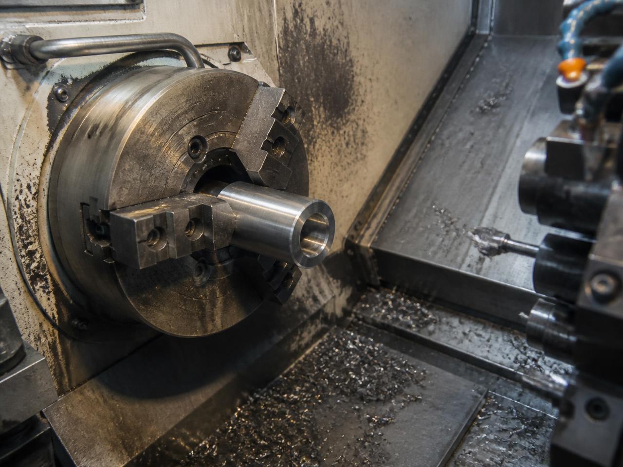 CNC lathe chuck holding a steel component in a working machine shop